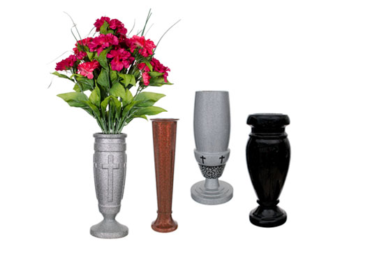 A selection of memorial vases in different styles and materials, including a gray vase with a cross design, a bronze vase, and a black polished vase, some adorned with fresh flowers.